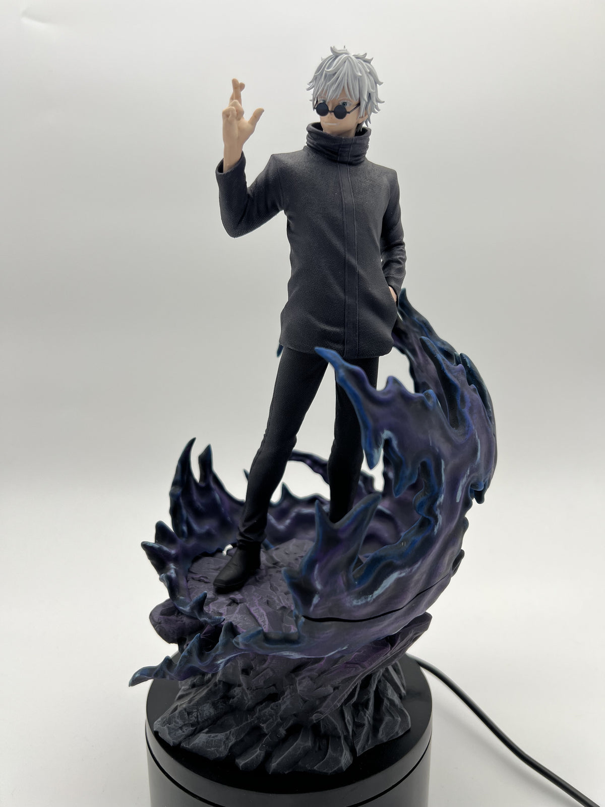 Hand-painted Gojo with white hair and round sunglasses, standing among blue and purple effects on a rocky base, by Cured Cove