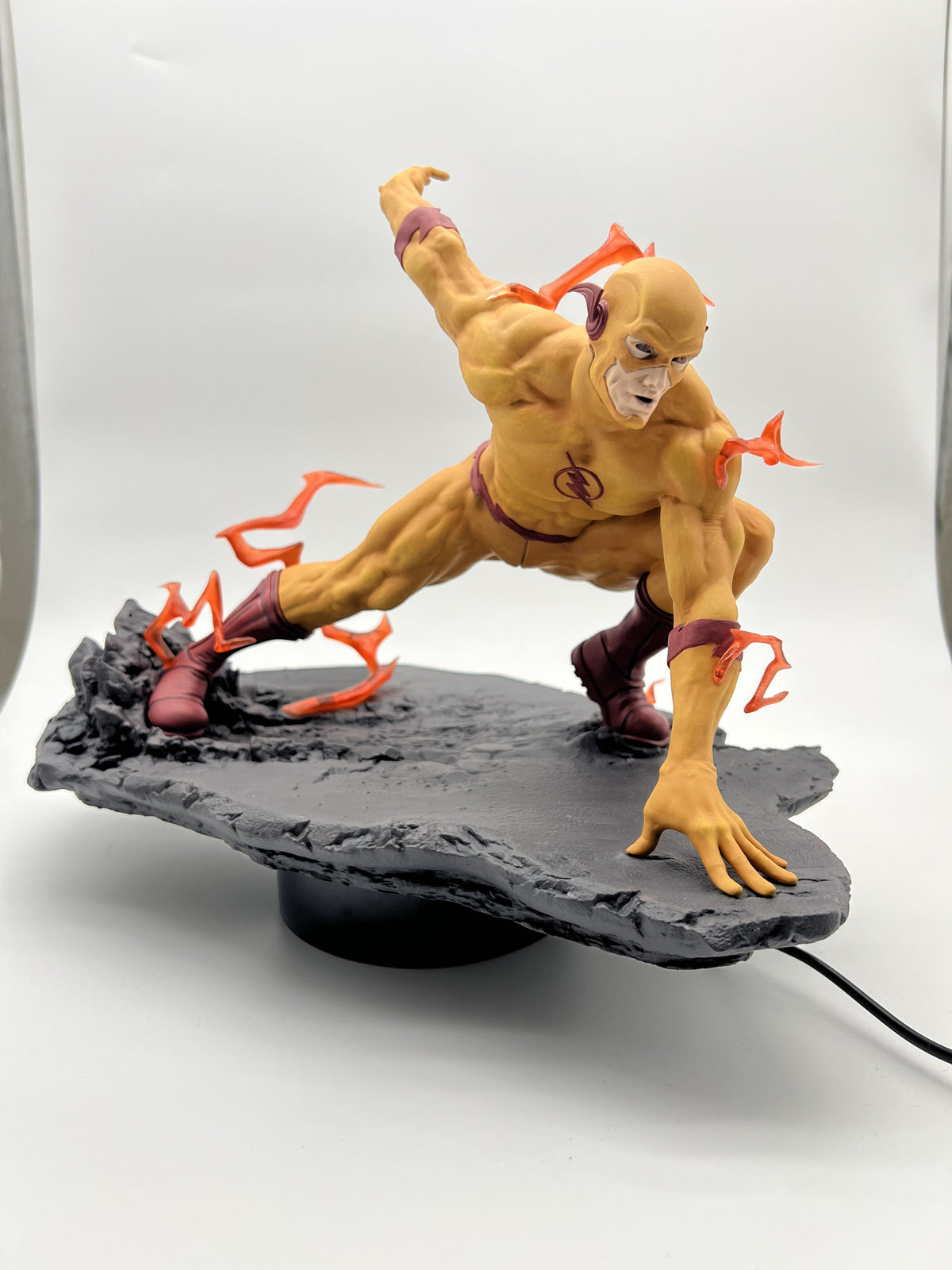 Hand-painted Reverse-Flash in a yellow suit with red lightning, crouching on a rocky road base, by Cured Cove